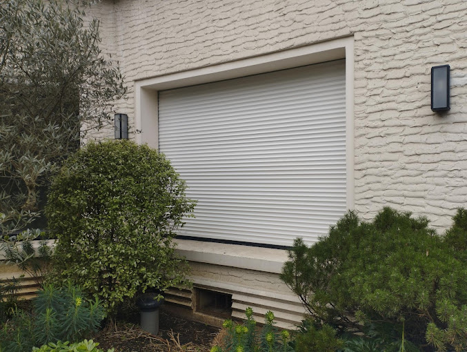 Volet roulant blanc traditionnel, lames aluminium donnant sur un jardin